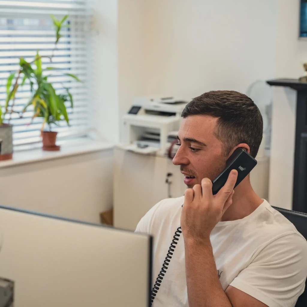 Property Manager on landline phone and looking at screen in Hackney Estate Agency office.